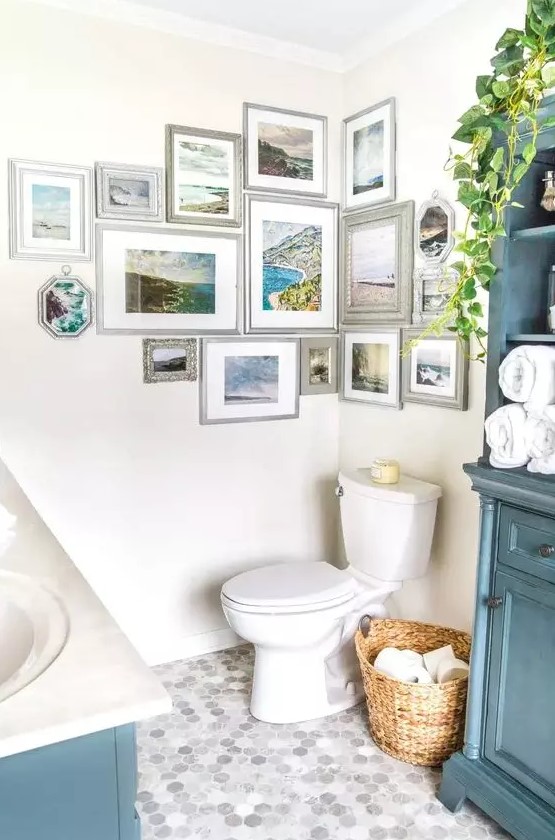 a coastal bathroom with blue furniture, a lovely seaside gallery wall, white appliances and potted greenery