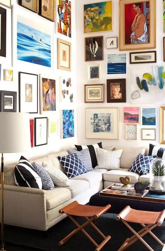 a colorful gallery wall taking two walls with mismatching frames and super bold artworks in various styles and in various colors