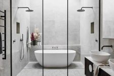 a contemporary bathroom clad with grey terrazzo tiles, a skylight over the tub, a black vanity and black framing, black fixtures