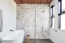 a contemporary bathroom with a stone accent wall, concrete tiles, a wood slab ceiling, neutral fixtures is chic