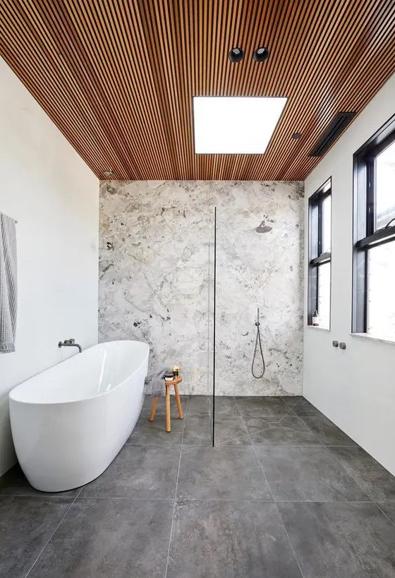 a contemporary bathroom with a stone accent wall, concrete tiles, a wood slab ceiling, neutral fixtures is chic
