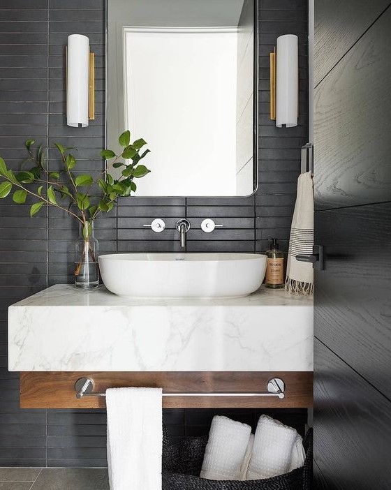 a contemporary bathroom with matte black skinny tiles on the wall plus a floating wood and marble vanity