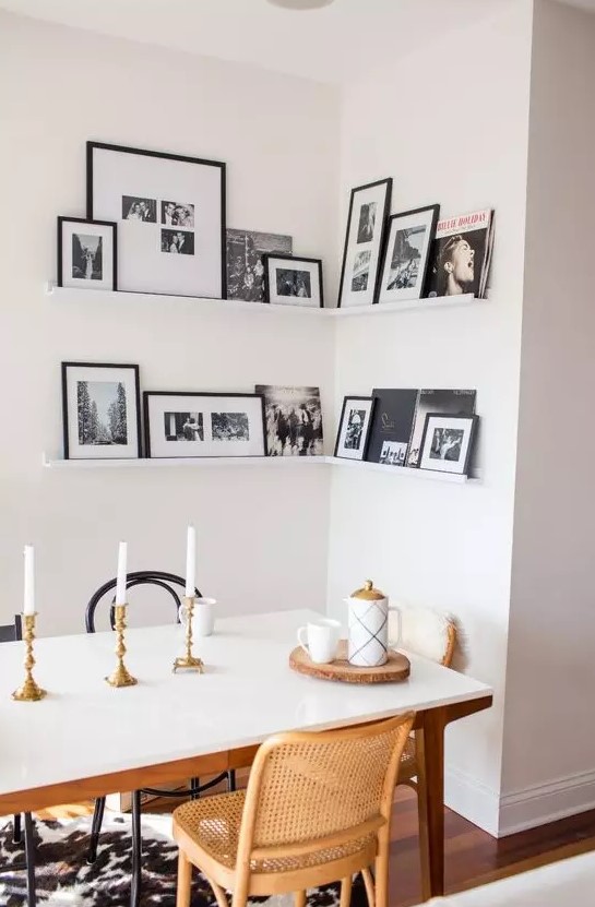 a corner gallery wall with black and white artworks in black frames adds personality to the space and makes it cozier
