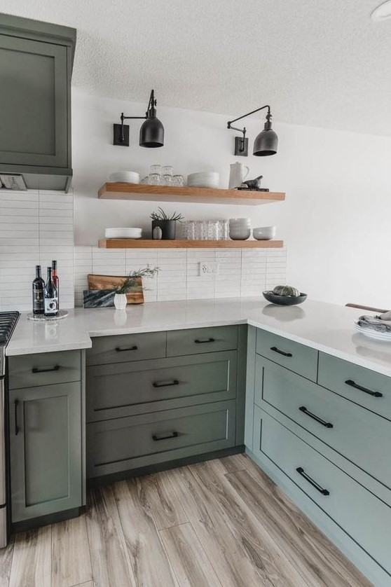a light green farmhouse kitchen with black fixtures and white stone countertops and a white stacked tile backsplash