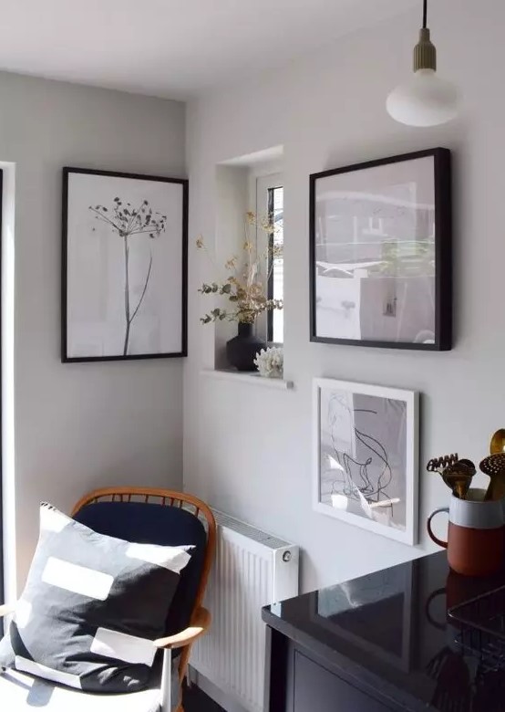 a lovely nook with a black chair with a pillow, a mini gallery wall and some dried blooms and plants