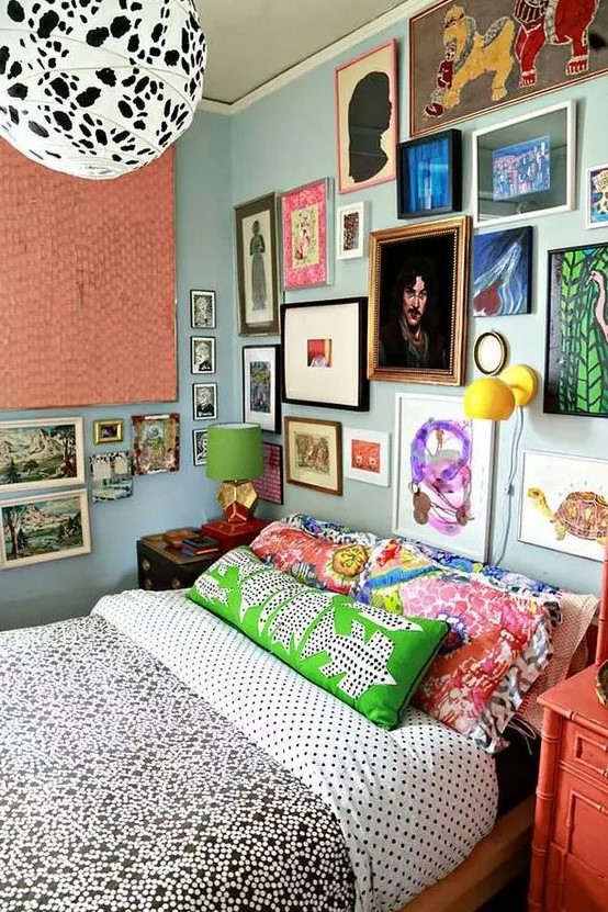 a maximalist gallery wall in various bright colors, with mismatching frames taking two walls looks very bold and cool