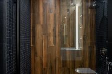 a minimalist bathroom clad with small black tiles and with wood-like tiles for a super elegant and contrasting look