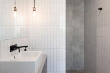 a minimalist bathroom done with grey tiles and white skinny ones for an eye-catchy touch