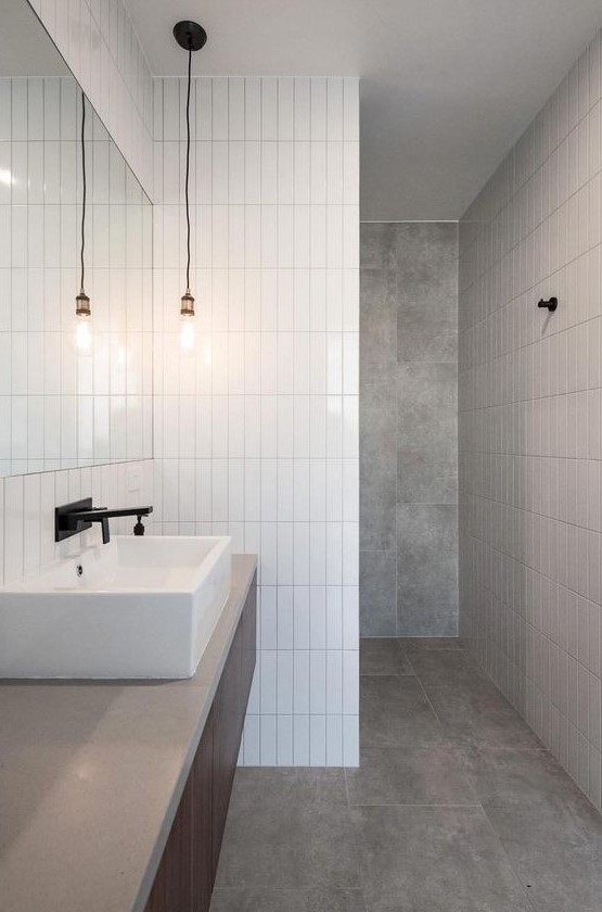 a minimalist bathroom done with grey tiles and white skinny ones for an eye-catchy touch