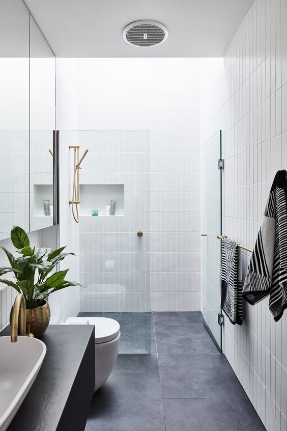 a minimalist bathroom with white stacked skinny tiles, large scale grey tiles, a dark-stained vanity and a sink, a potted plant