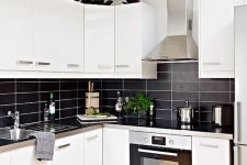 a modern contrasting kitchen with white cabinets, a black stacked tile backsplash and metal countertops is extra bold