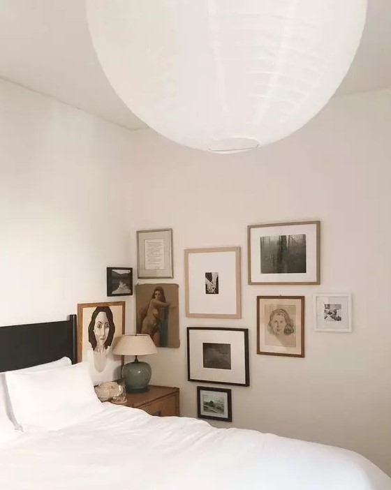 a neutral bedroom with a vintage feel, a black bed with white bedding, a vintage-inspired corner gallery wall is amazing
