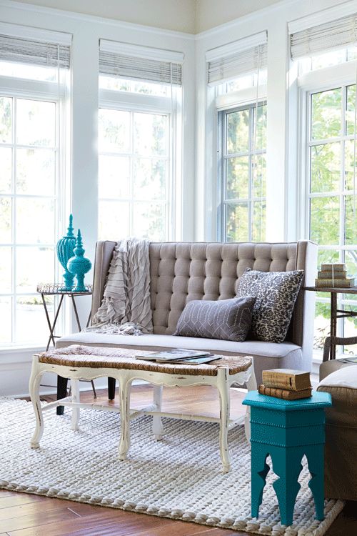 a neutral interior with a greige loveseat, a vintage coffee table, bold blue and turquoise touches for more interest