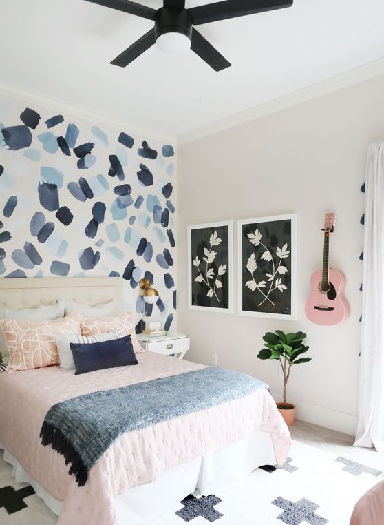 a pretty teen bedroom with a brushstroke accent wall, pink and blue textiles and a pink guitar on the wall