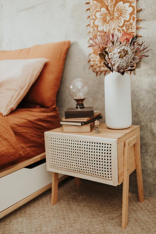 a small and pretty mid-century modern nightstand with a cane webbing door in white for a boho or mid-century modern space