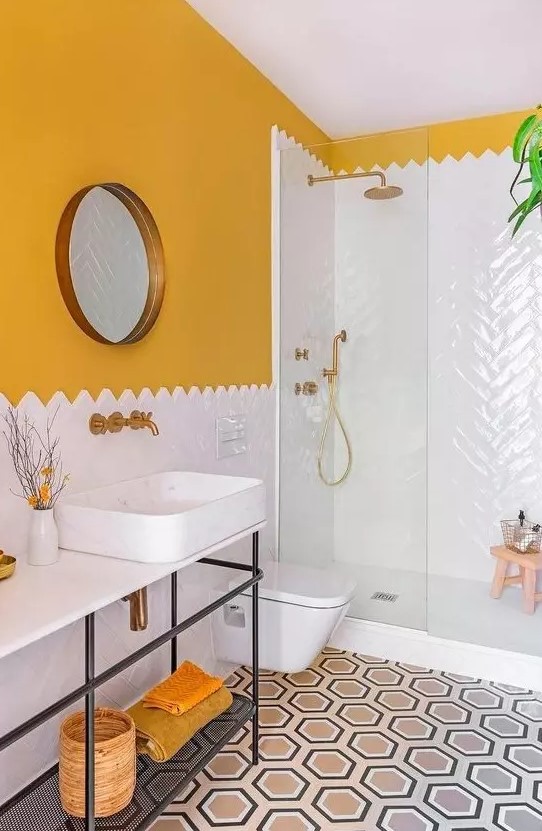 a stylish bathroom with a sunny yellow wall, white tiles, a round mirror and a neutral and lighweight vanity