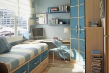 a stylish small blue and tan teen room with a bed with drawers for storage, a corner desk and a curved wardrobe, floating shelves and stacked books