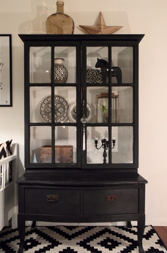 a vintage black armoire with usual drawers and glass doors that allow you display beautiful things inside and make them stand out