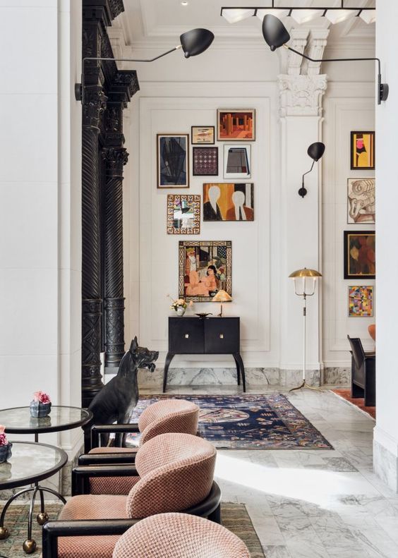 a whimsical interior with a bright gallery wall, a black vintage dresser, glass tables and rust chairs is a beautiful space