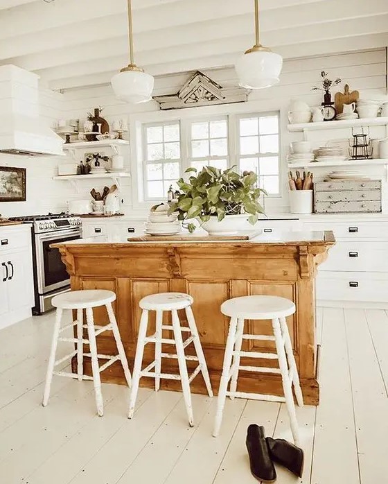 a white Scandinavian kitchen with shaker style cabinets, a light-stained kitchen island, pendant lamps and white stools