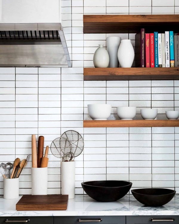 an elegant modern farmhouse kitchen with white stacked skinny tiles on the backsplash, open shelves, black cabinetry and white marble countertops