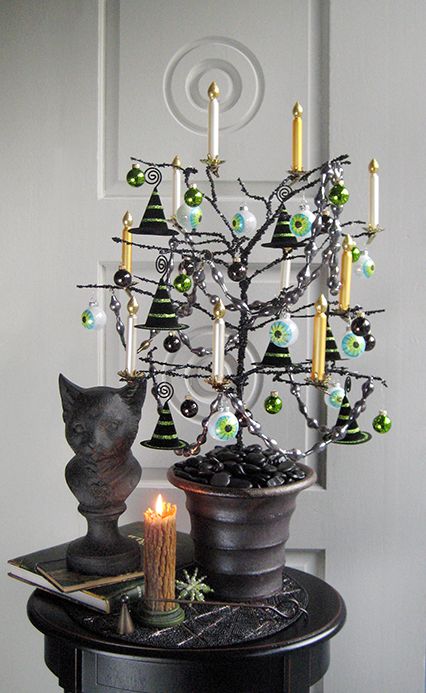 a black Halloween tree with black and green ornaments, large eyeball ones, white and gold candles is amazing