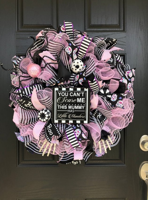 a fun black, pink and white Halloween wreath with lots of mesh ribbons and striped ones, ornaments, donuts and a sign