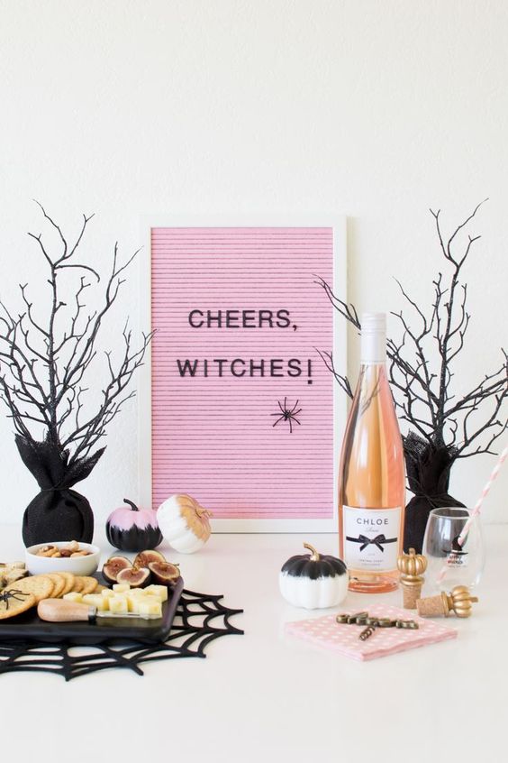 a Halloween dessert table with a pink letterboard, some black, gold and pink pumpkins, drinks and cookies is modern and fresh