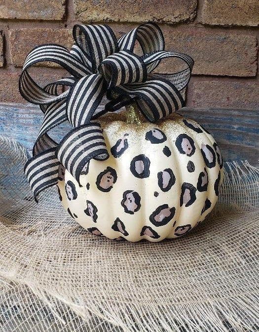 a leopard pumpkin decorated with simple sharpies, with a bit of gold glitter on top and a striped bow is a cool and bold idea for Halloween