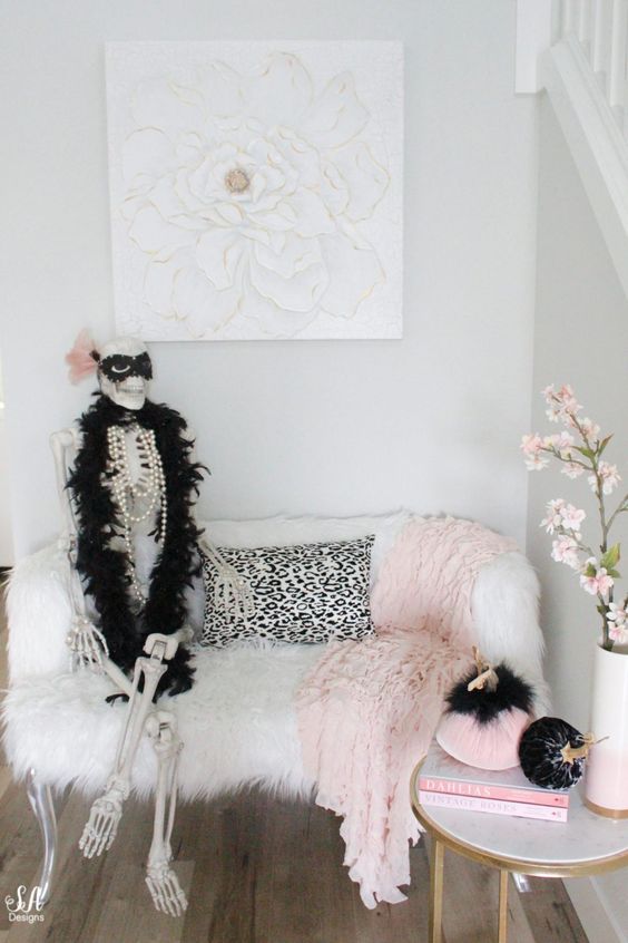 glam entryway decor with pink and black velvet pumpkins, a pink blanket and a skeleton dressed up in a glam way