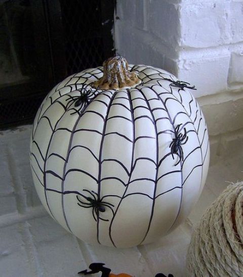 a super simple and cool Halloween pumpkin design done with a sharpie and black plastic spiders is a lovely idea to try