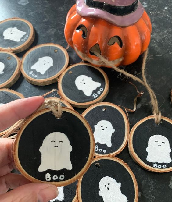 black chalkboard tree slice ornaments with white ghosts on them are a cute rustic Halloween decor idea