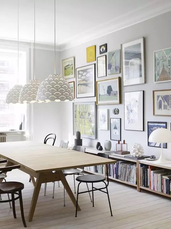 a Scandinavian dining room with a modenr table and black chairs, a free form colorful gallery wall and bookshelves