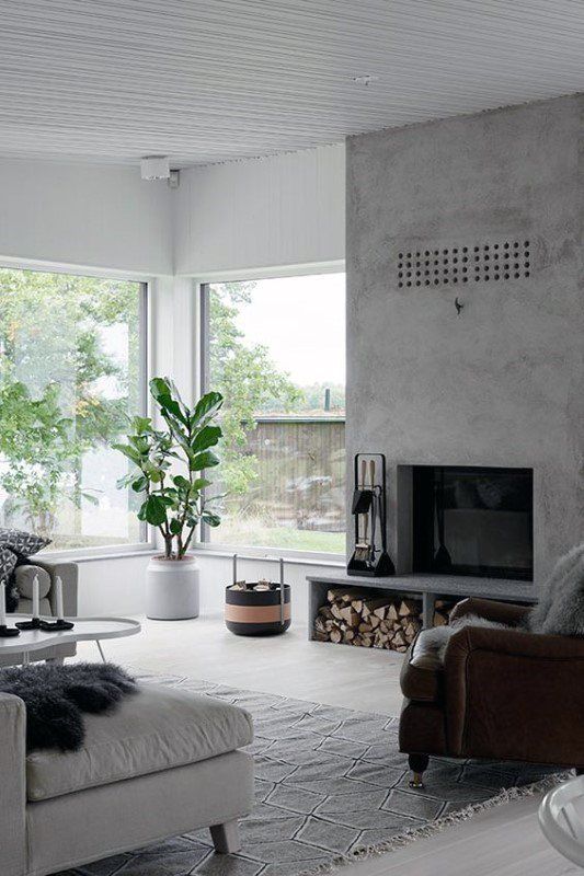 a Scandinavian living room with a concrete fireplace, neutral seating furniture, potted plants and printed textiles