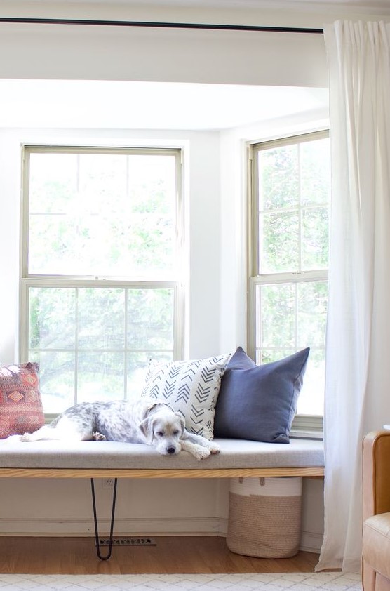 a bay window with a fitted daybed, colorful pillows, a basket and curtains to make this space private