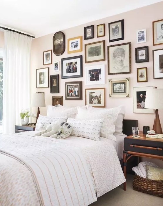 a beautiful bedroom with a blush accent wall done with a vintage gallery wall, a black bed with neutral bedding and black nightstands