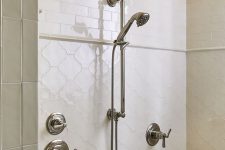 a beautiful neutral shower space clad with creamy skinny and arabesque tiles, with vintage fixtures and a built-in bench