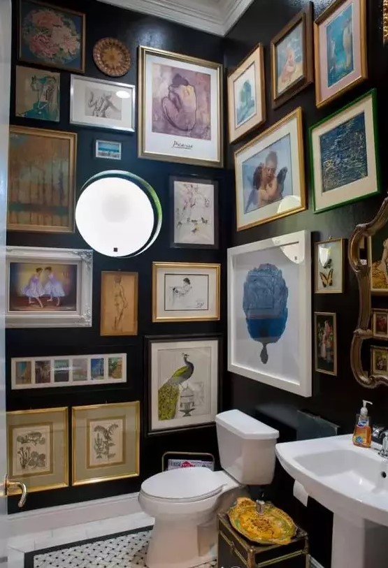 a black powder room with a round window, vintage artwork all over the space, white appliances and lights here and there