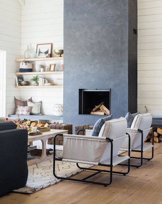 a bold and catchy living room in neutrals, with a grey concrete fireplace and benches with niches for storing firewood