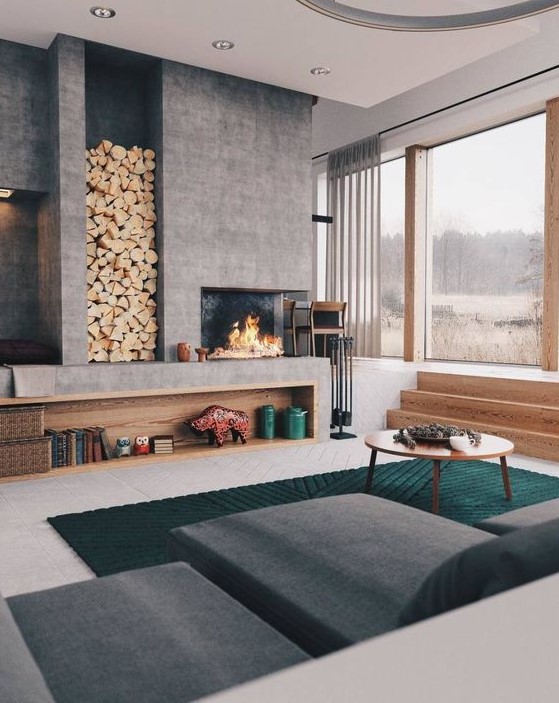 a bold and cool modern living room with a large concrete fireplace and a niche for storing firewood is very welcoming