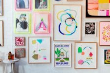 a bright gallery wall with abstract artworks and prints, with neon ligth frames and usual ones for a funky look