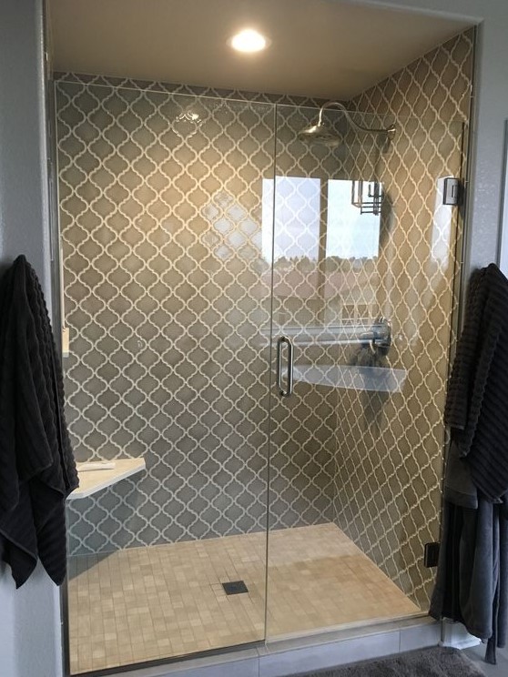 a chic shower space with grey arabesque tiles with white grout to make them stand out and grey marble tiles on the floor looks very eye-catchy