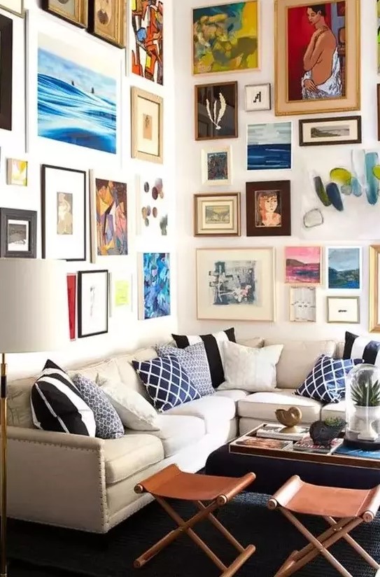 a colorful gallery wall taking two walls with mismatching frames and super bold artworks in various styles and in various colors