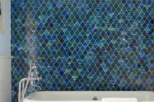 a contemporary bathroom with a fantastic blue and green arabesque tile accent wall plus a white chic bathtub is amazing