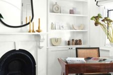 a creative and refined home office with a built-in storage unit, a metal fireplace, an asymmetrical mirror in a black mirror, black and white curtains, a rich stained desk and a rattan chair