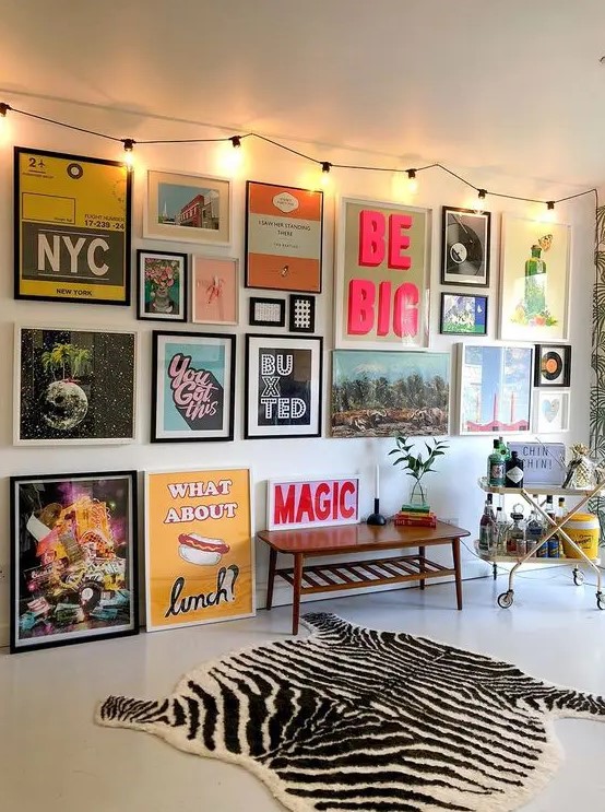 a creative gallery wall with bold and unusual artworks and posters in mismatching frames is a very bold idea