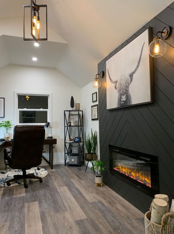 a farmhouse home office with a built-in fireplace clad with grey planked, a dark stained corner desk, a leather chair and potted plants