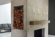 a large concrete fireplace with marble tiles, a rough wood slab, a niche for storing firewood and a potted plant