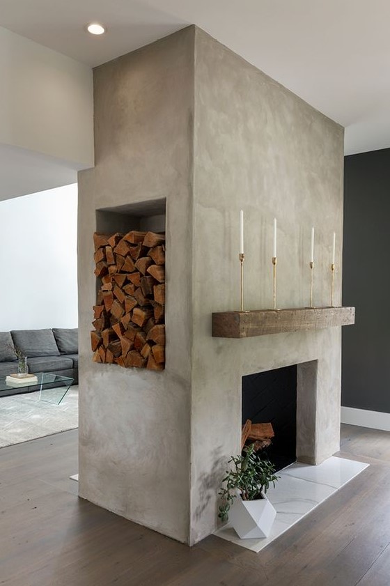a large concrete fireplace with marble tiles, a rough wood slab, a niche for storing firewood and a potted plant