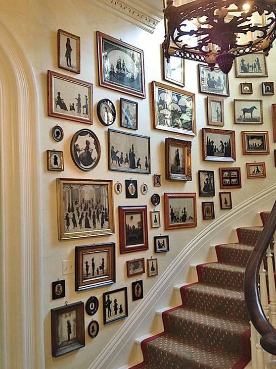 a large gallery wall with mismatching vintage frames and black and white artworks with a strong elegant vintage feel